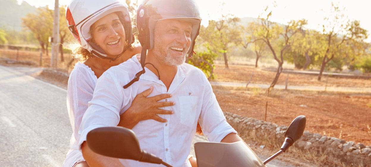 Mature couple riding motor scooter